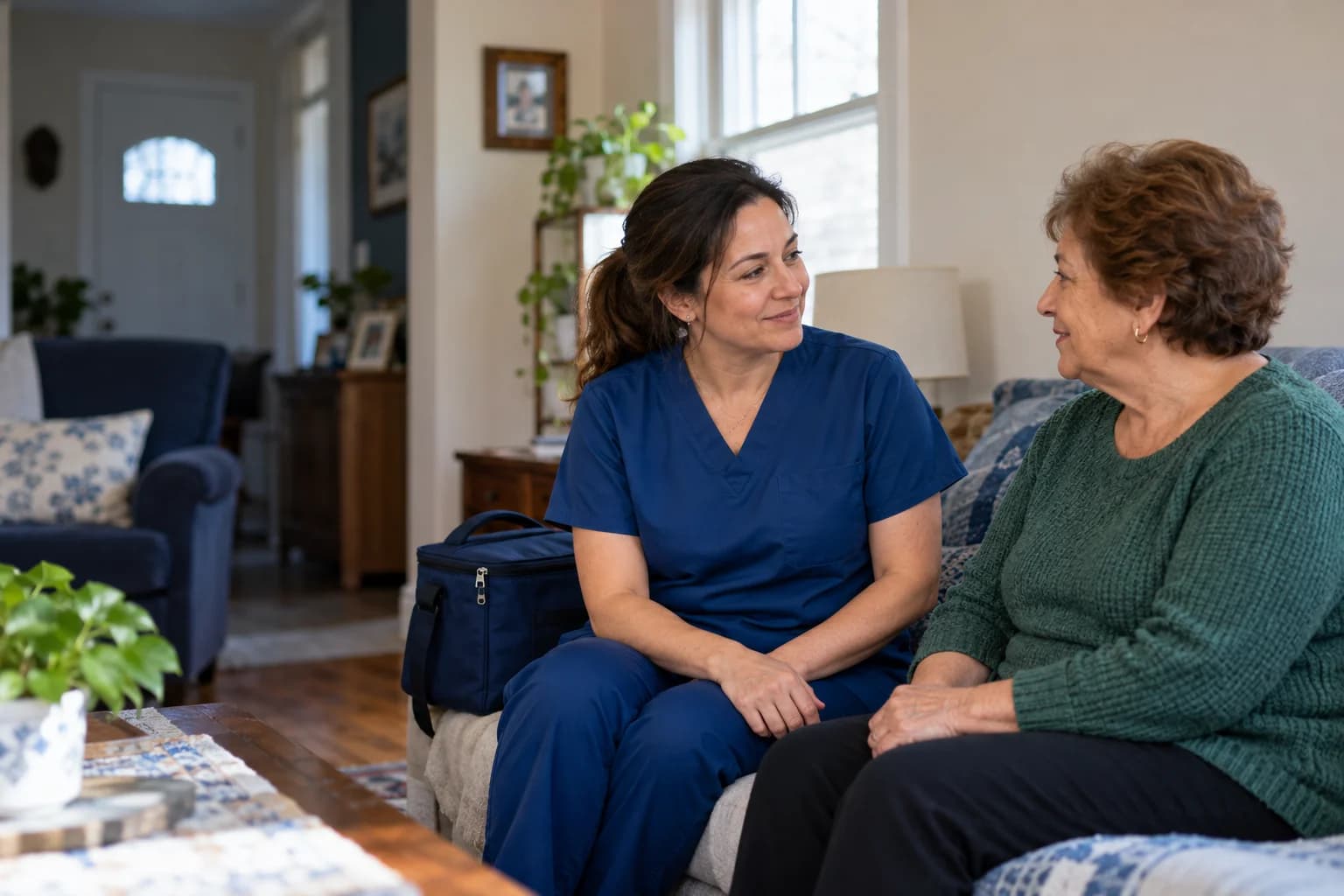 A healthcare professional talking with an older adult during a home visit
